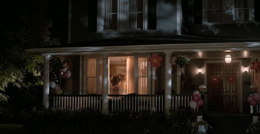 Lee Garner viewed through a lit window returning to his family home at night, symbolizing forgiveness, facing guilt, and emotional liberation.