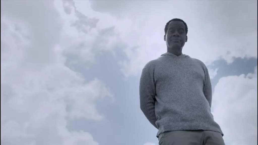 Lee Garner smiling peacefully under a bright sky after escaping hell by confronting his guilt—a visual metaphor for self-forgiveness and emotional liberation in Lucifer.
