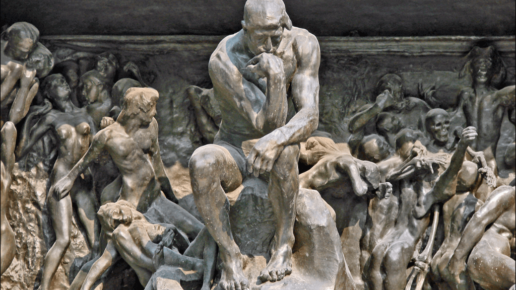 Bronze sculpture of The Thinker by Auguste Rodin seated above a chaotic scene from The Gates of Hell.
