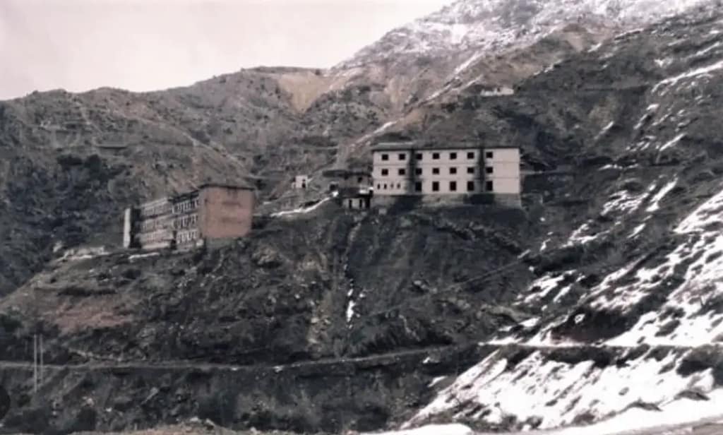 Distant view of prison of spac building on a snowy, rugged mountain slope, symbolizing isolation and oppression