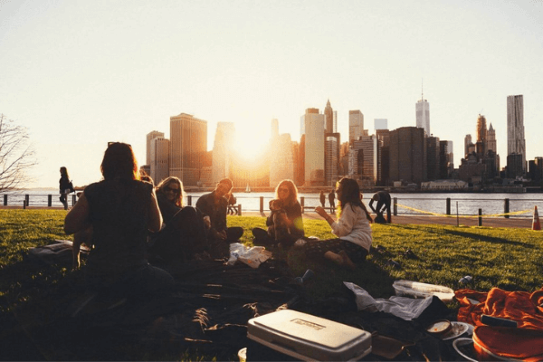 Friends enjoying a picnic at sunset in a city park, promoting relaxed social interaction.