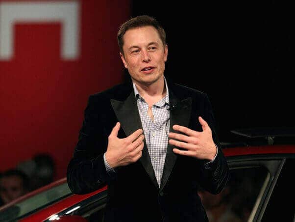 Elon Musk speaking confidently on stage, representing visionary optimism and persuasive communication.