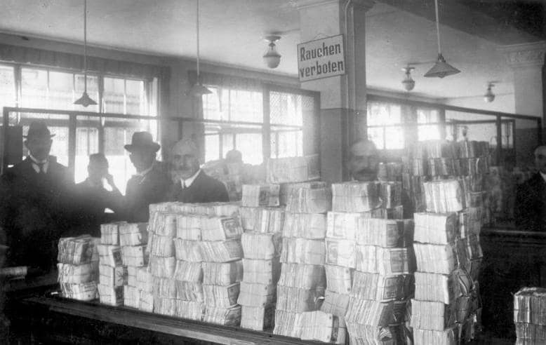 Bank employees surrounded by towering stacks of devalued banknotes during Germany’s 1920s hyperinflation crisis.