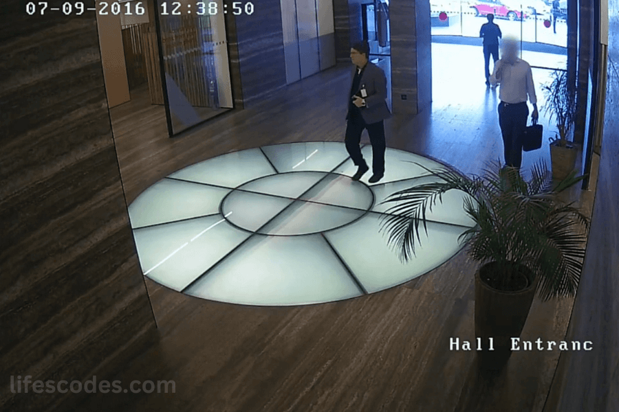 Security camera footage of a man entering an office building lobby during daytime