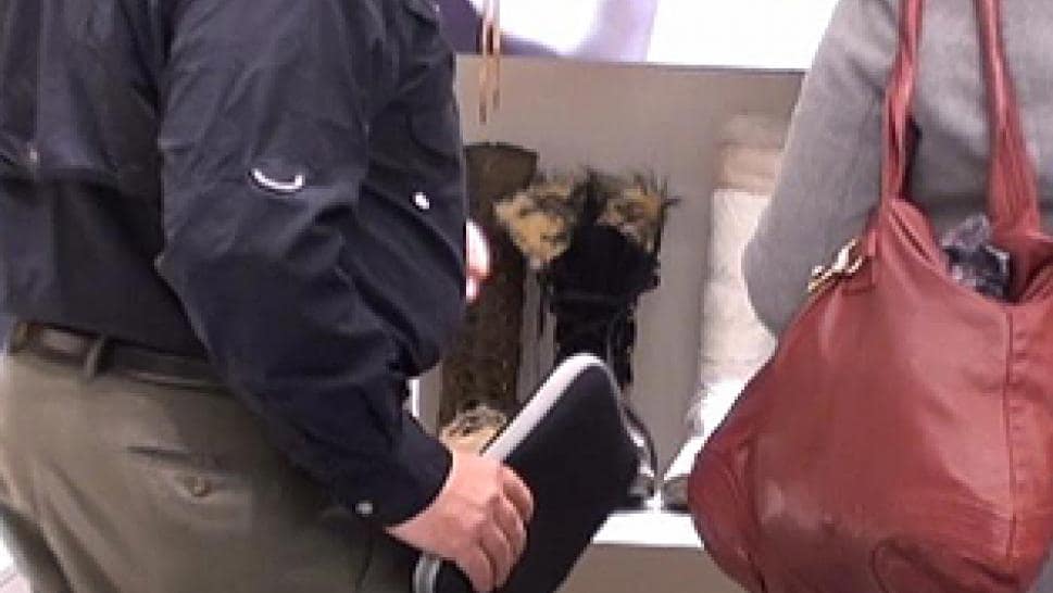 Person discreetly holding an RFID scanner near a woman’s purse to perform electronic pickpocketing, a social engineering technique.