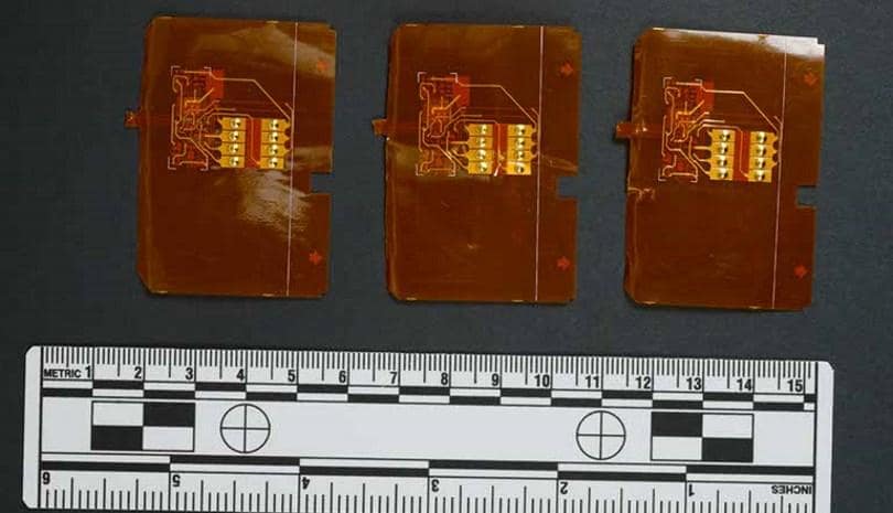 Three thin shimming devices for stealing credit card data, shown with a ruler for scale, illustrating social engineering tools.